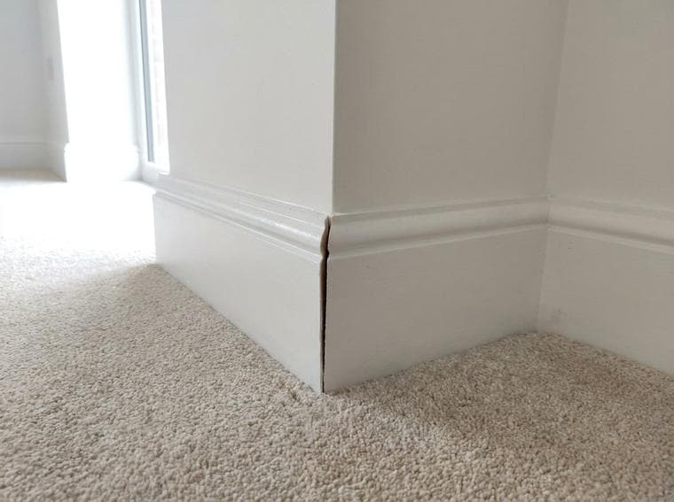 The outside-corner miter joint in the baseboard is open, with an unfinished gap between the two sections.