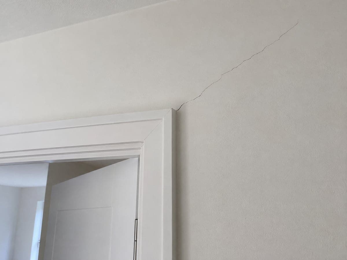 A fine diagonal crack runs through the painted finish above the upper corner of the door opening.
