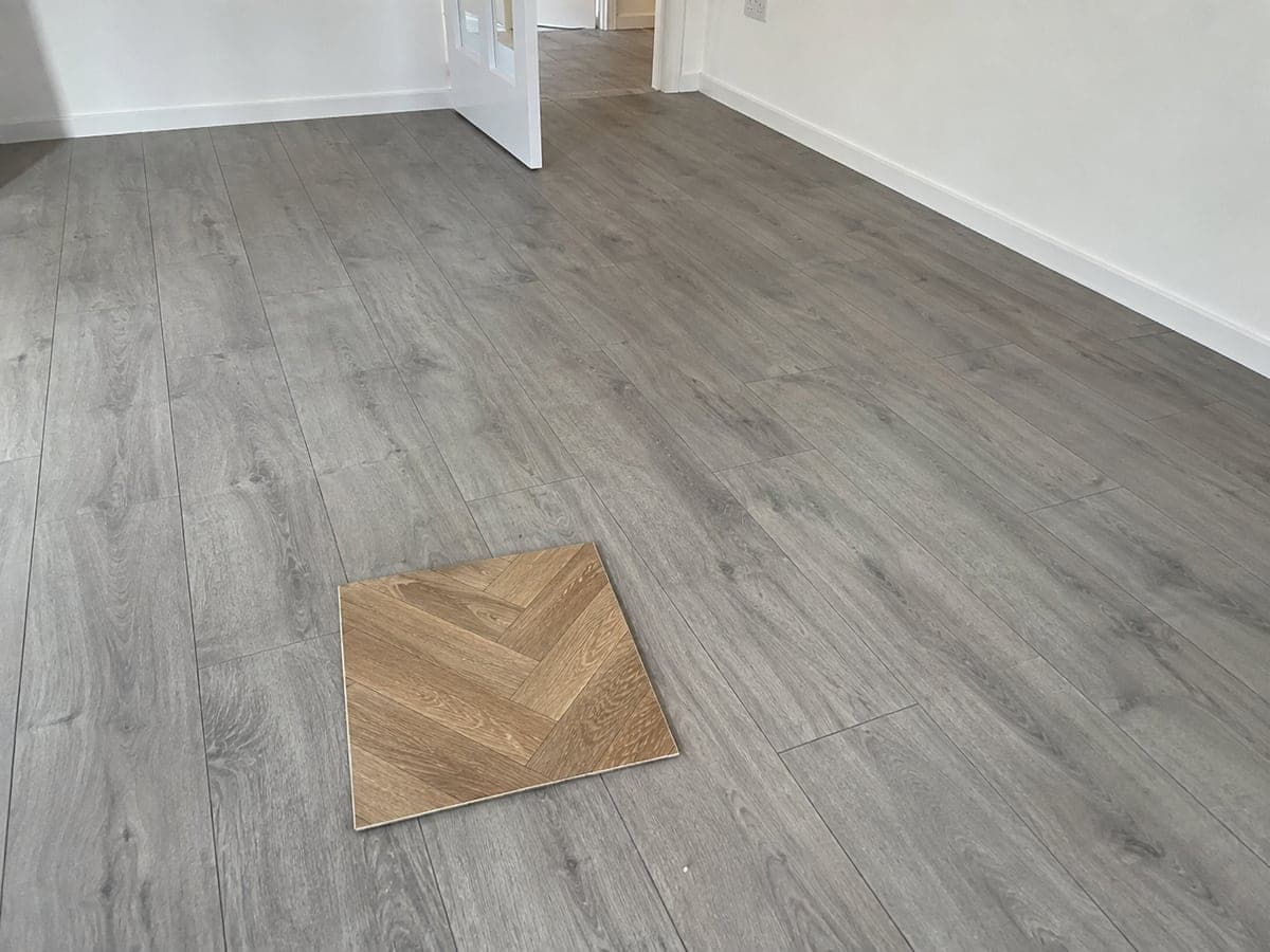 Gray straight-laid planks have been installed. The homeowner confirmed warm oak parquet as the selected finish and showed the approved sample during the visit.